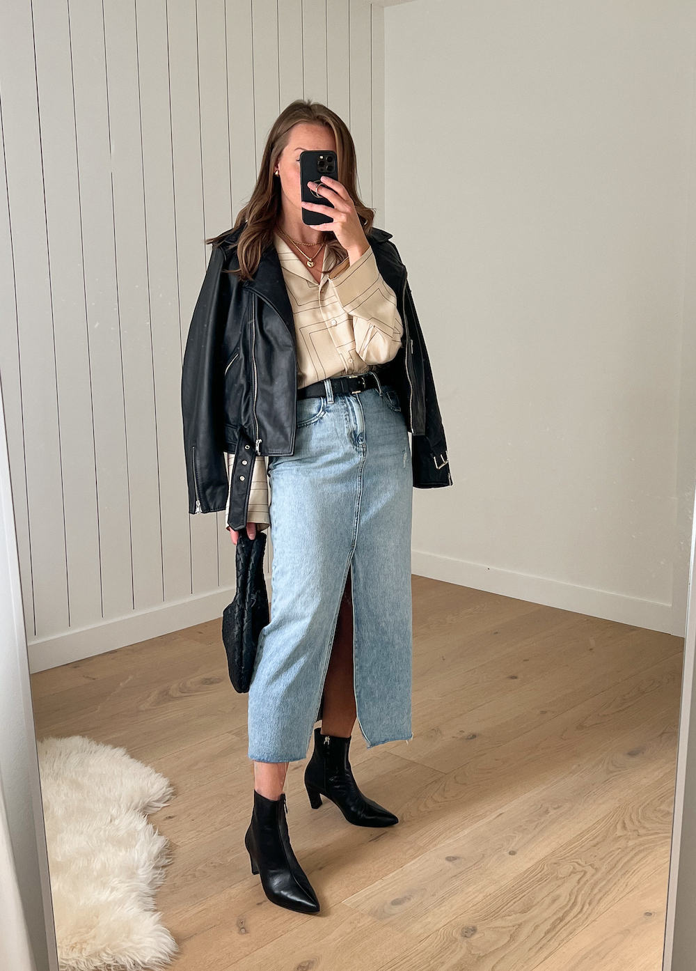 Christal wearing a denim midi skirt with a button down and a leather jacket.