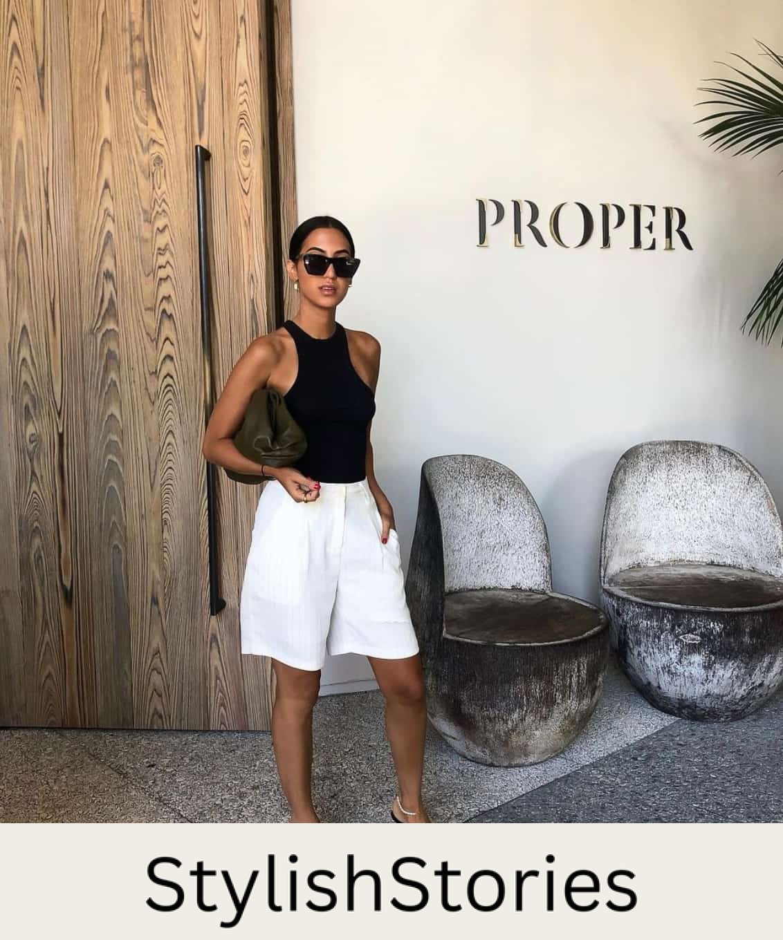 woman wearing a black tank with long white pleated shorts and black kitten heel sandals at a winery