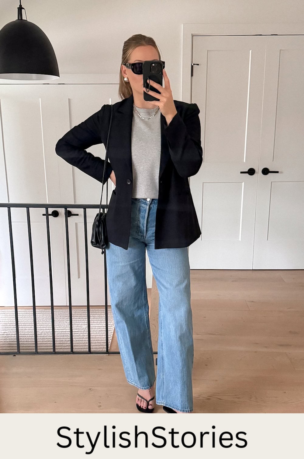 Christal wearing light wash wide leg jeans, a grey sweater and a black blazer.