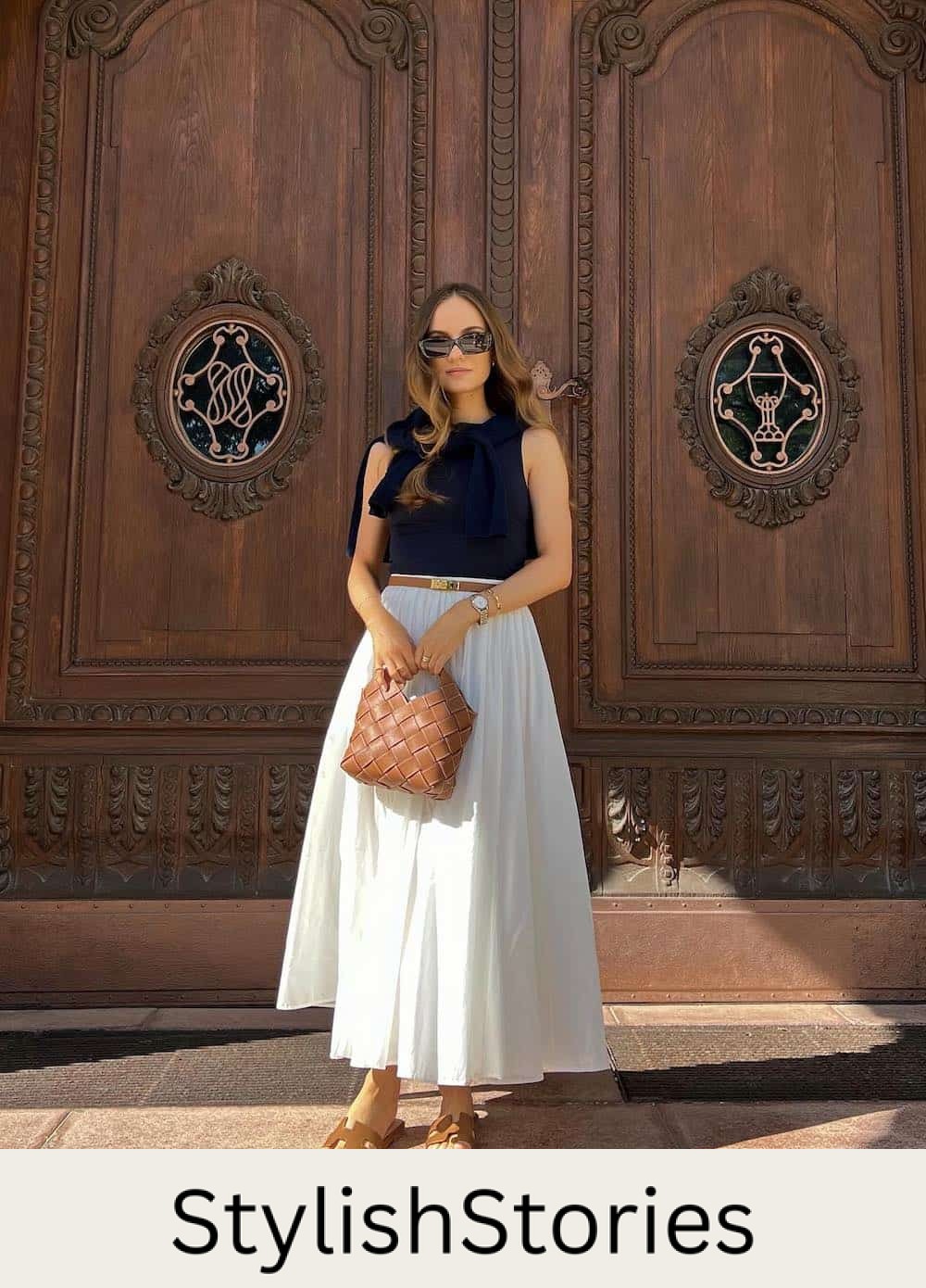 woman wearing a black tank top, tan belt, and full white cotton maxi skirt with brown sandals
