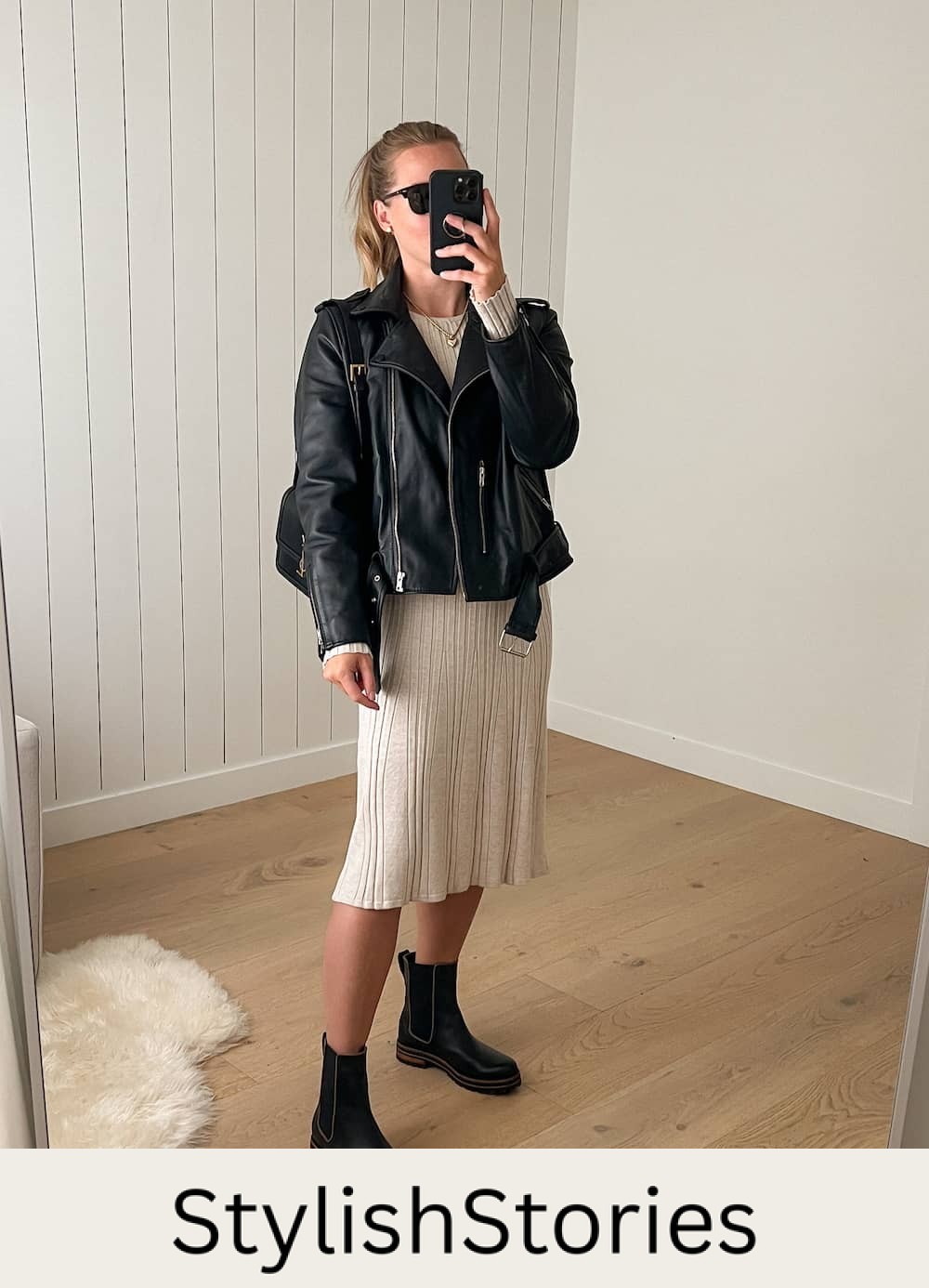 woman wearing a leather jacket over a beige sweater dress with black lug boots for a winter concert 