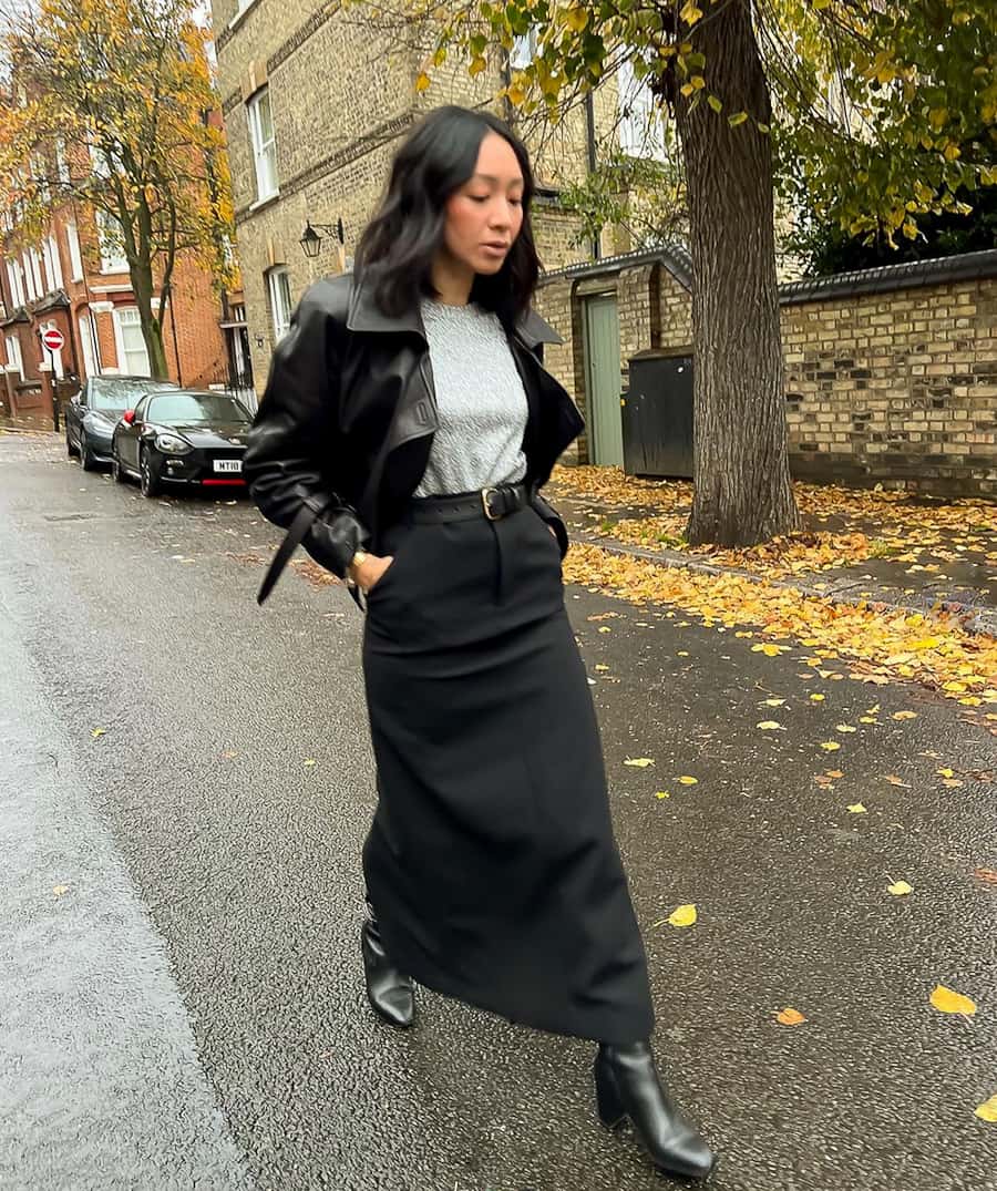 woman wearing a black leather jacket with a long black denim skirt and boots