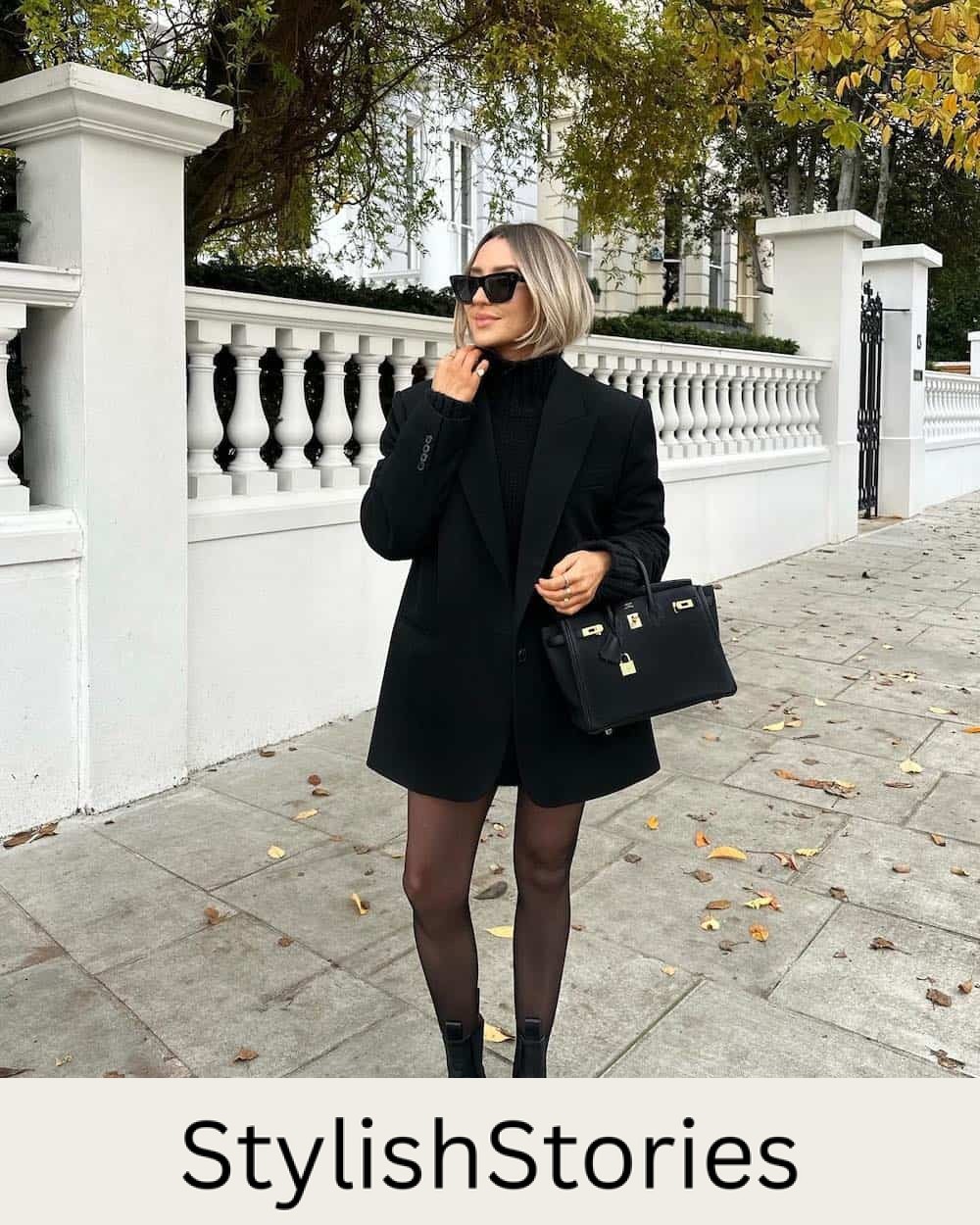 Woman wearing lugg boots, black tights, and a long black leather blazer over a black sweater dress.