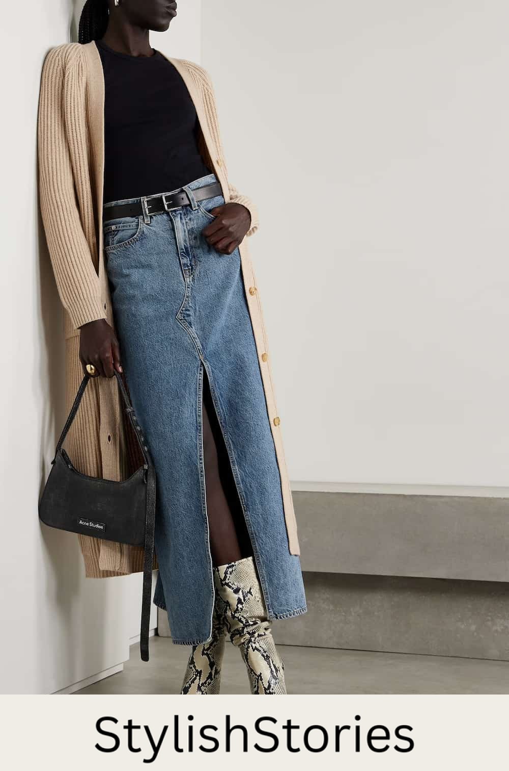 Woman wearing a long denim skirt with snakesin booties and a long tan cardigan.