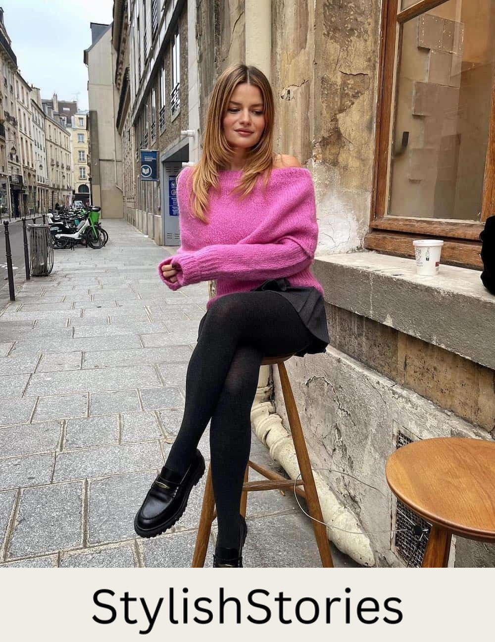 Woman wearing a black skirt with loafers and a pink sweater.