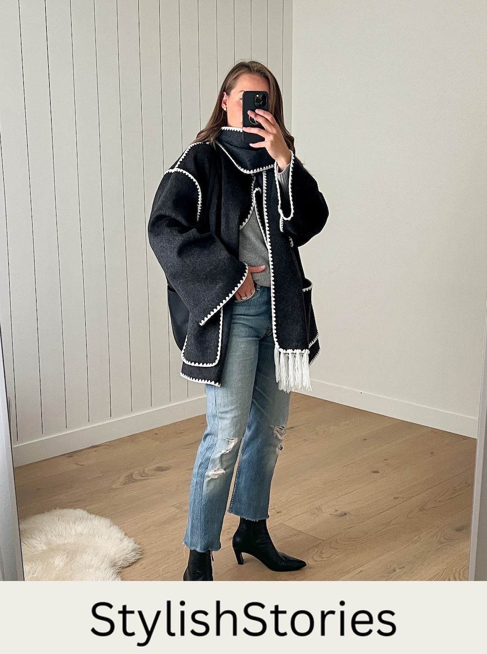 Christal wearing distressed jeans with black booties and a black and white scarf and coat.