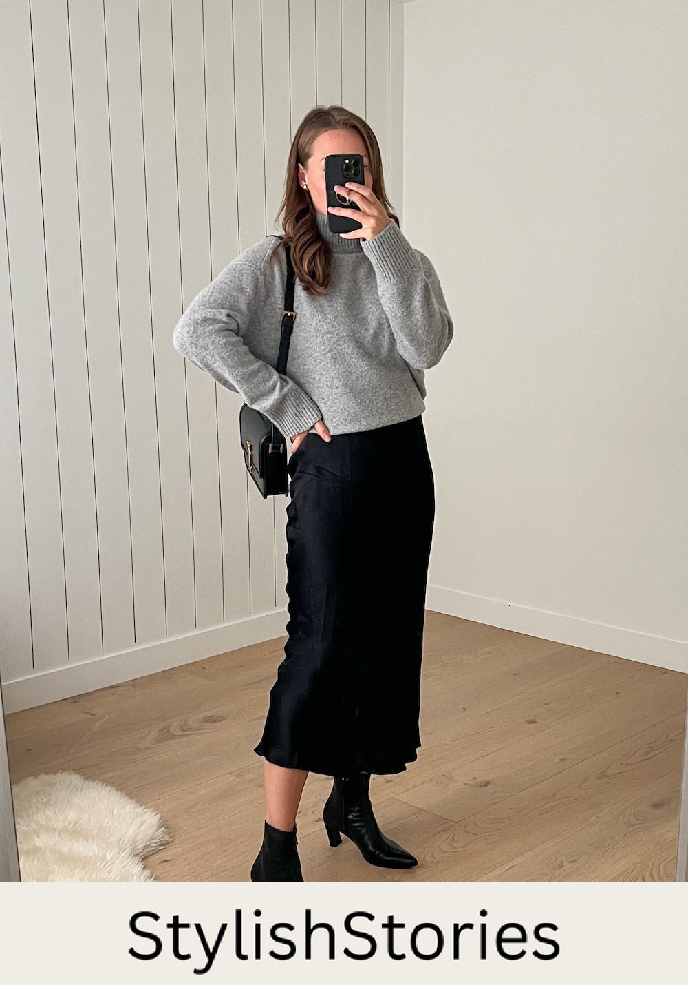 Christal wearing a black slip skirt with black booties and a grey sweater.
