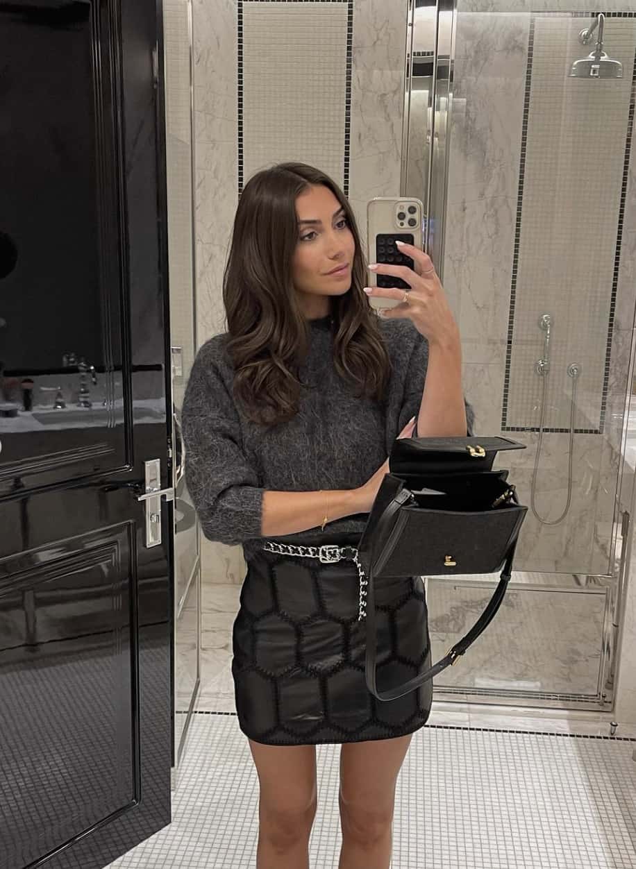 woman wearing a winter going out outfit with a grey sweater and black skirt
