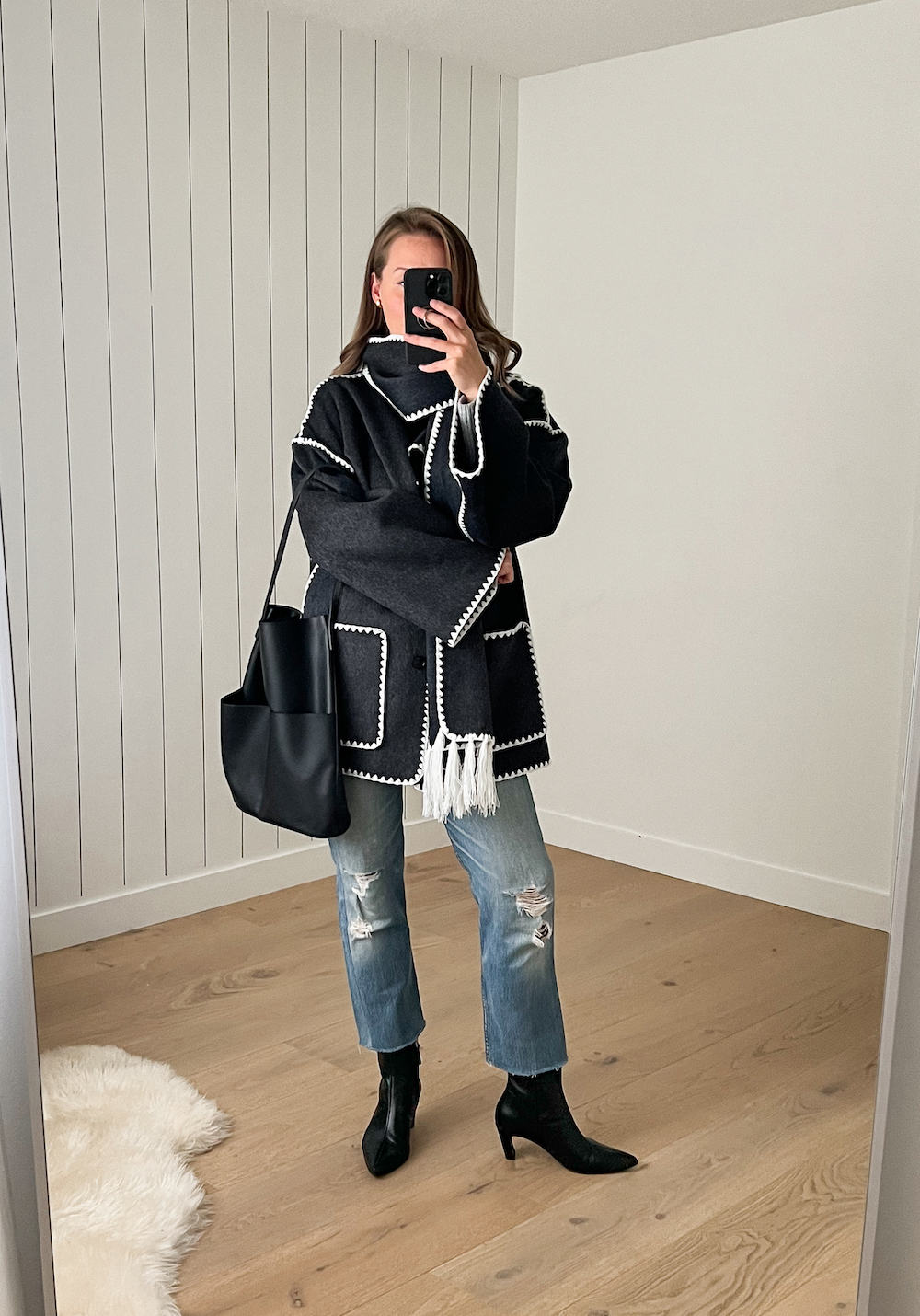 Christal wearing jeans with black booties and a black coat with matching scarf.