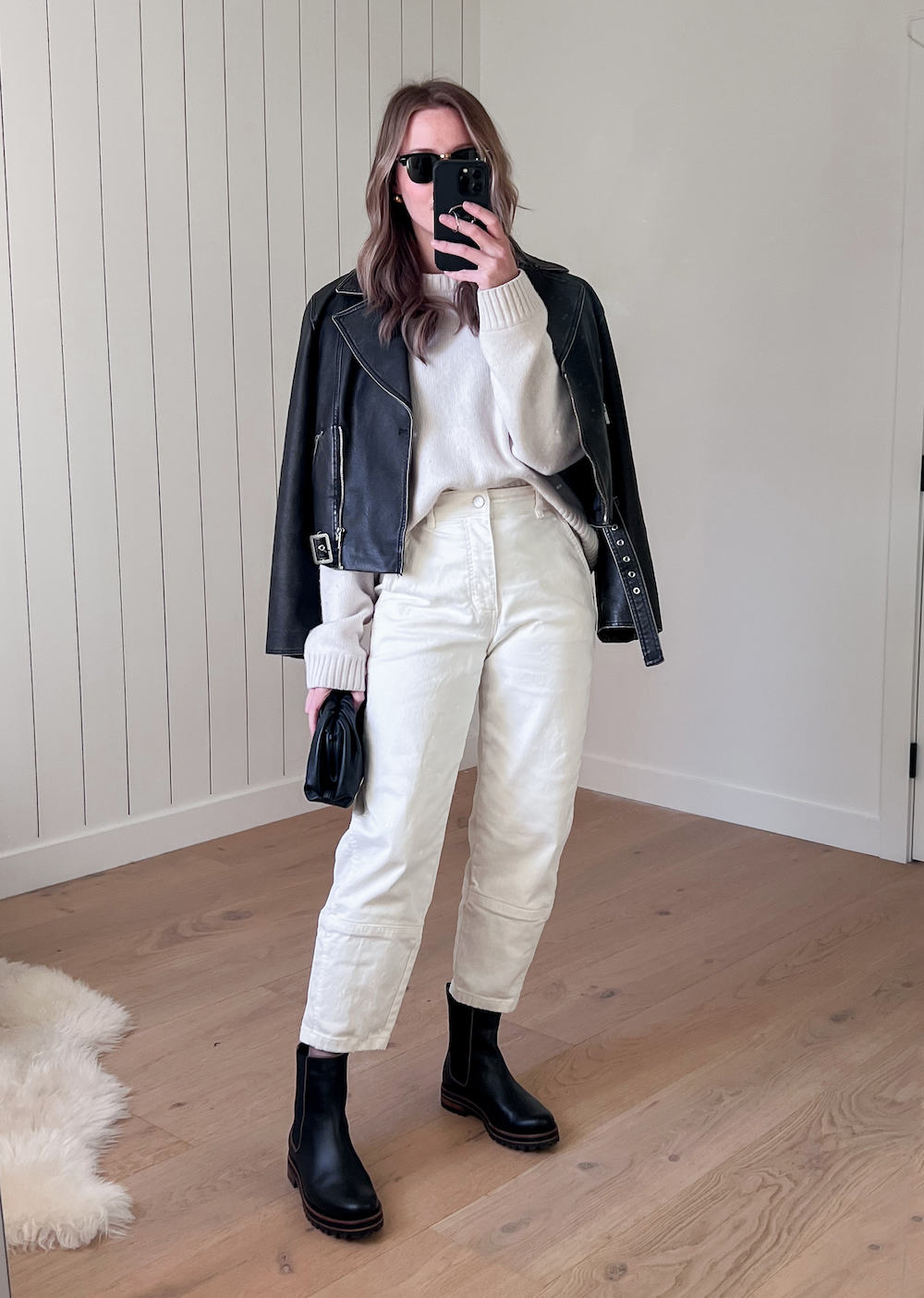 Christal wearing white pants with a white sweater and a black leather jacket