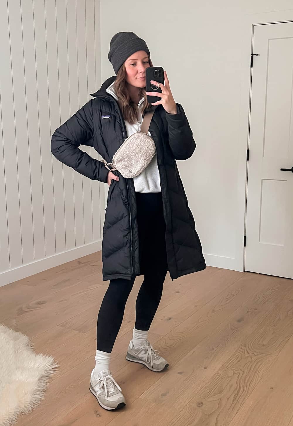 Christal wearing leggings with a white pullover and a black puffer coat.
