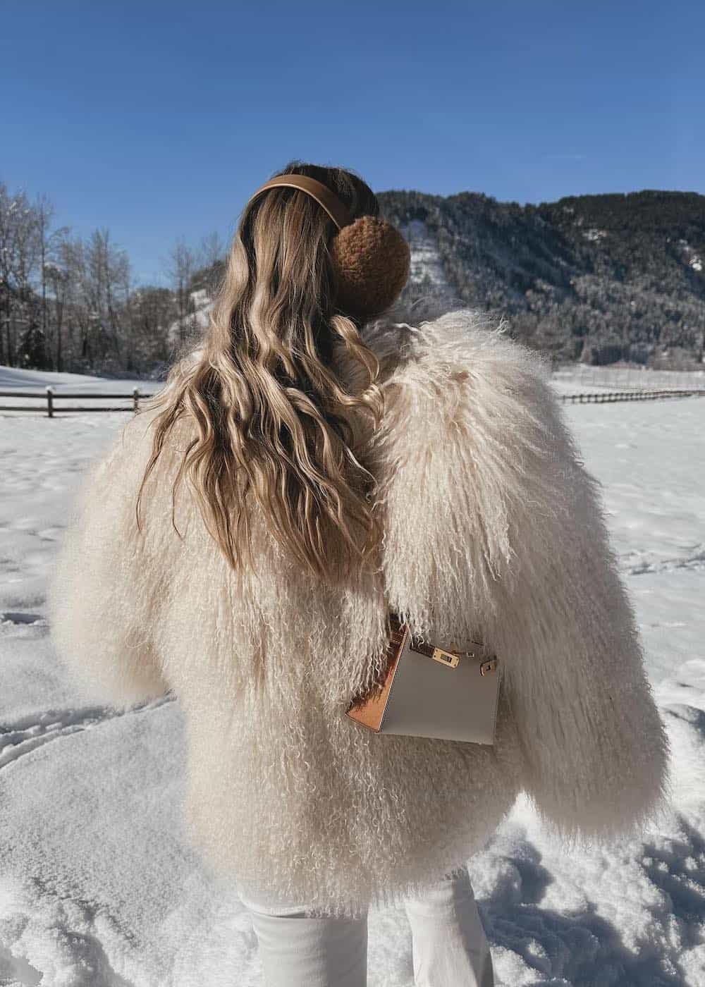 Woman wearing an all white textured coat in the snow.