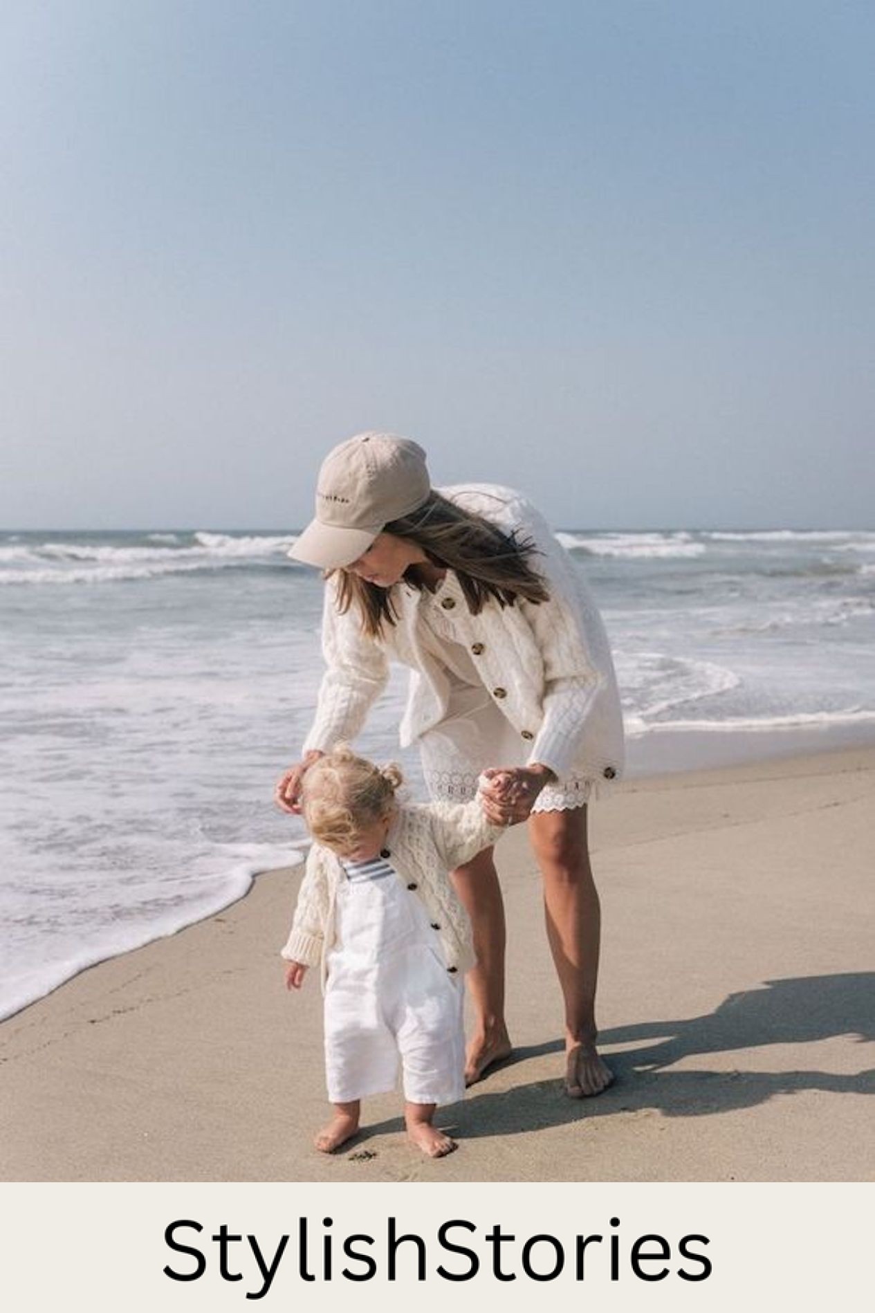 image of a mother and daughter at the beach with the ocean in the background wearing white clothing with ivory knit sweaters
