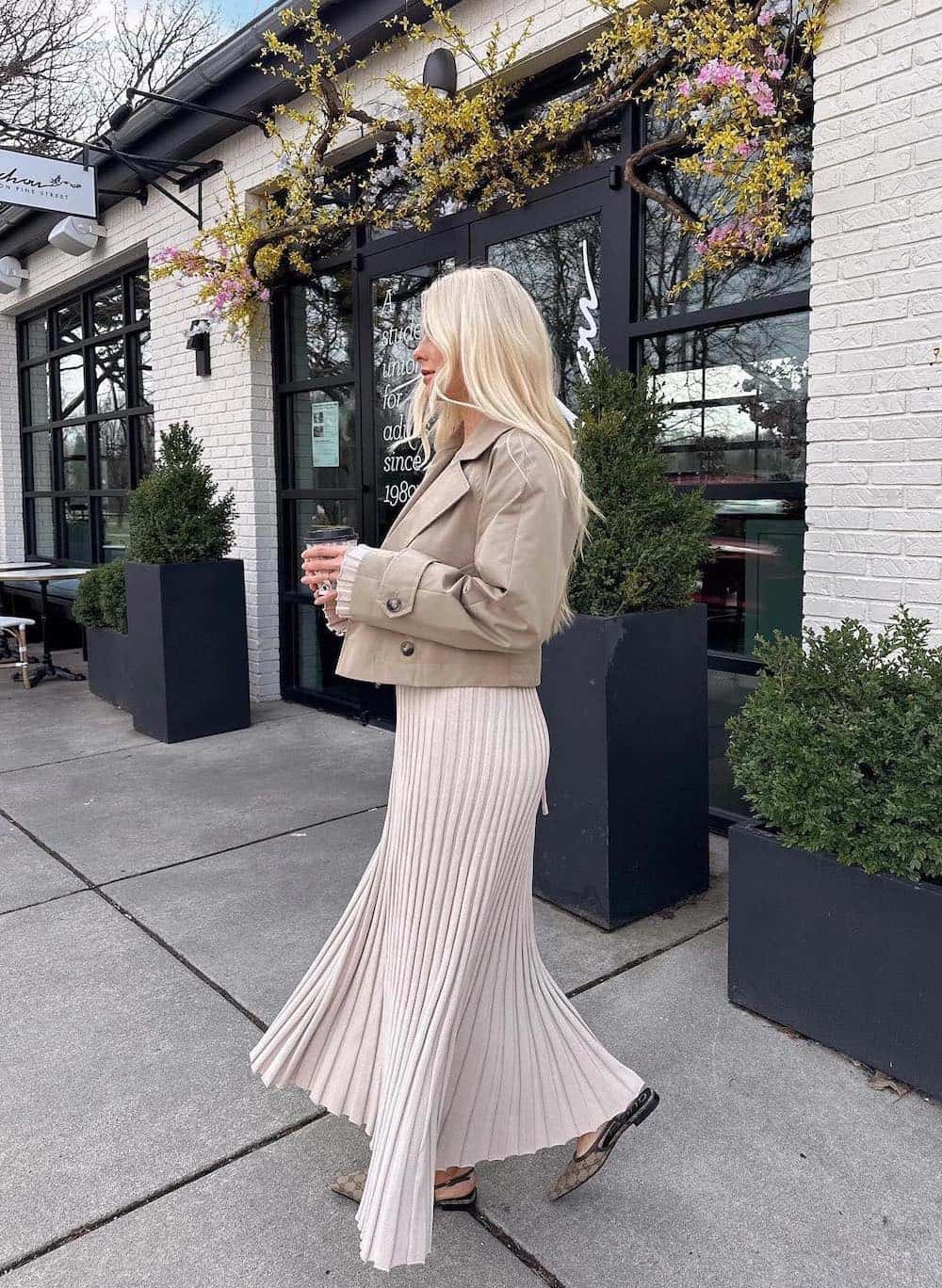 Woman wearing a tan, ribbed sweater dress with a cropped jacket.
