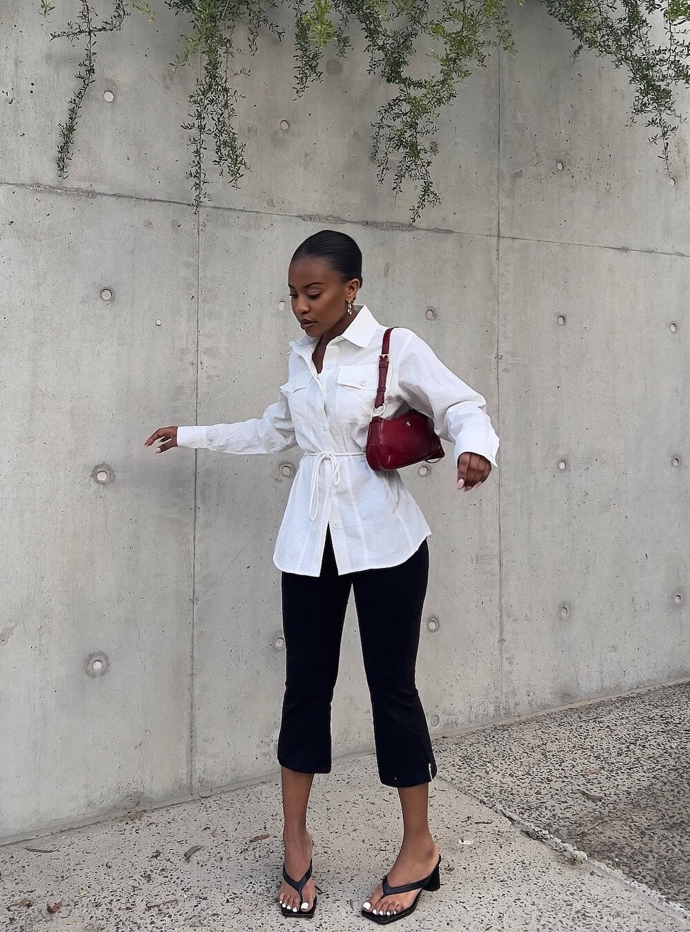 Woman wearing a white wrap top with black capri pants and heeled sandals.
