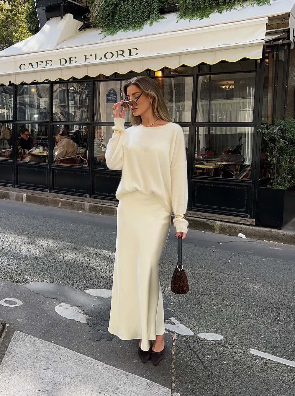 Woman wearing a cream silk skirt with a cream sweater and brown pumps.