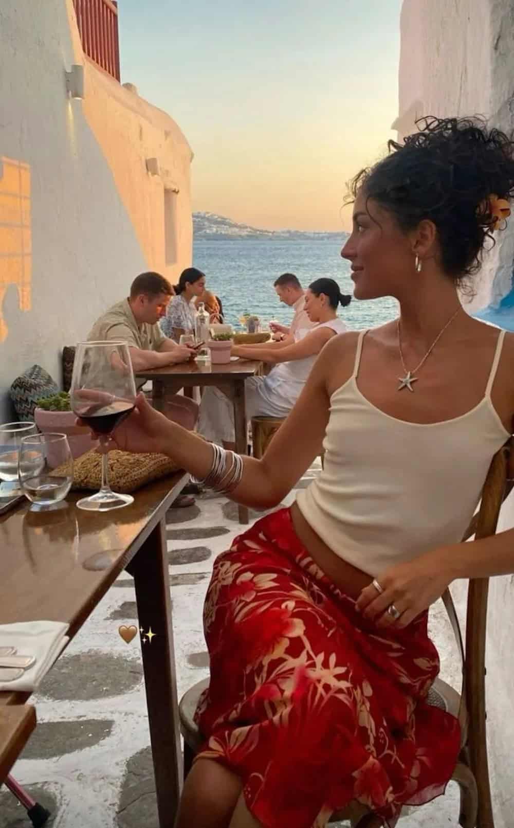 Woman wearing a floral print midi skirt with a white tank.