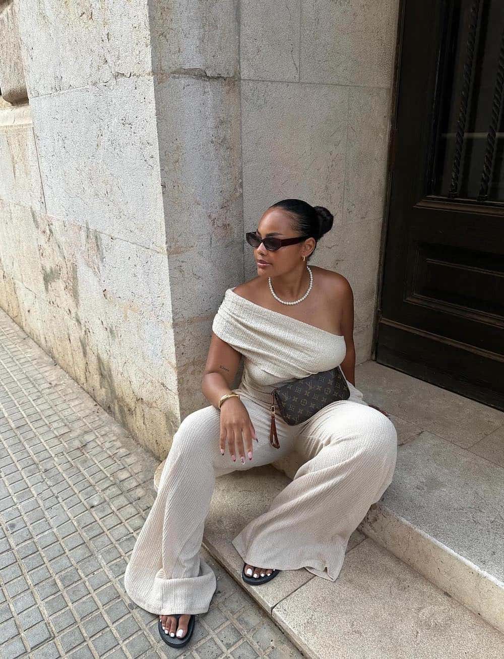 Woman wearing gauzy pants with a one shoulder top.