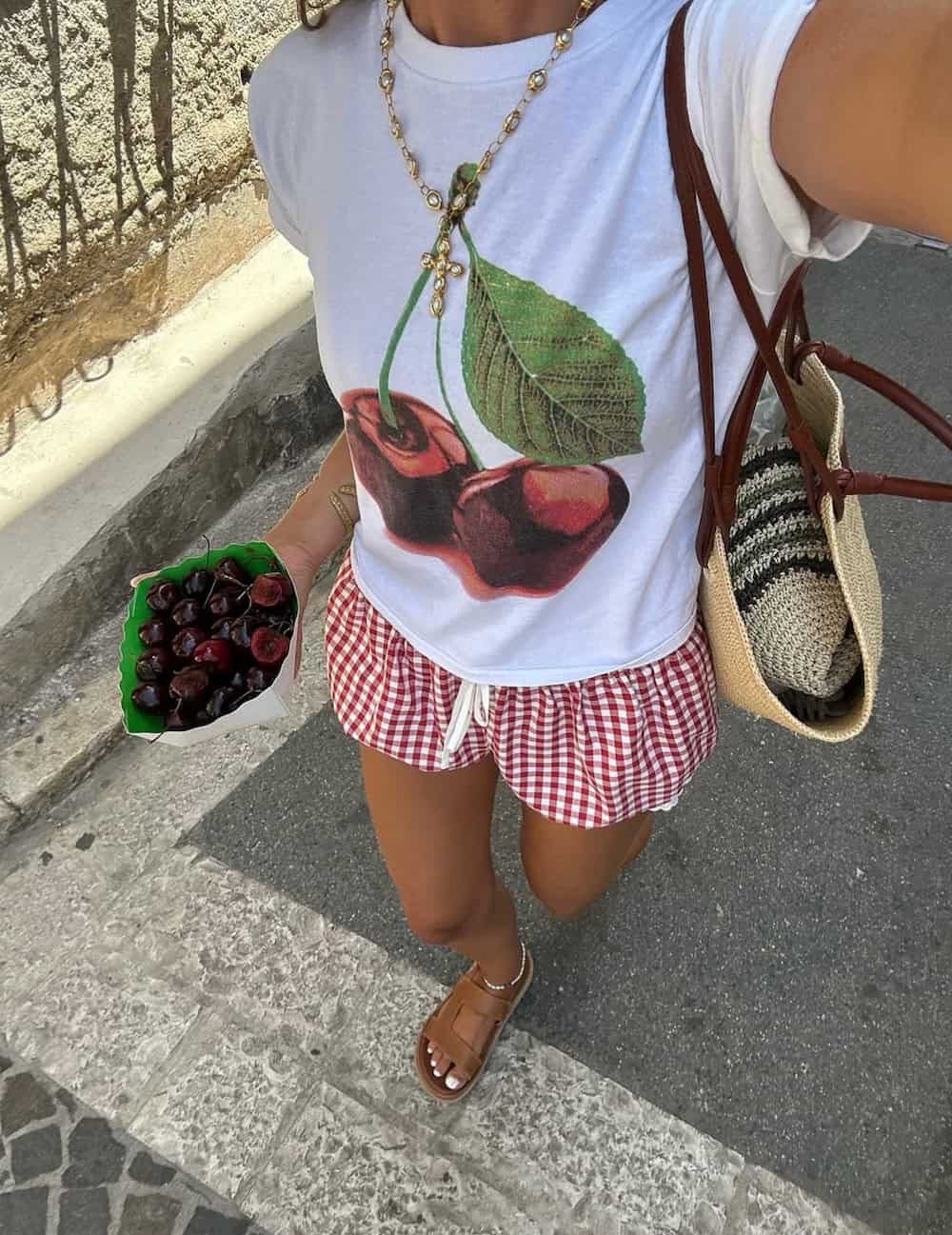 Woman wearing red and white gingham shorts with a white graphic tee.