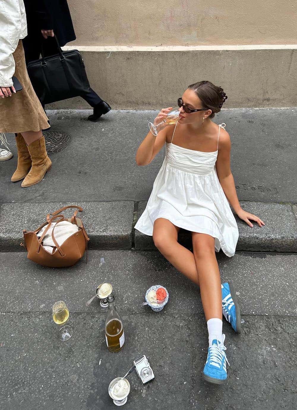 Woman wearing a white cotton sundress with blue sneakers.
