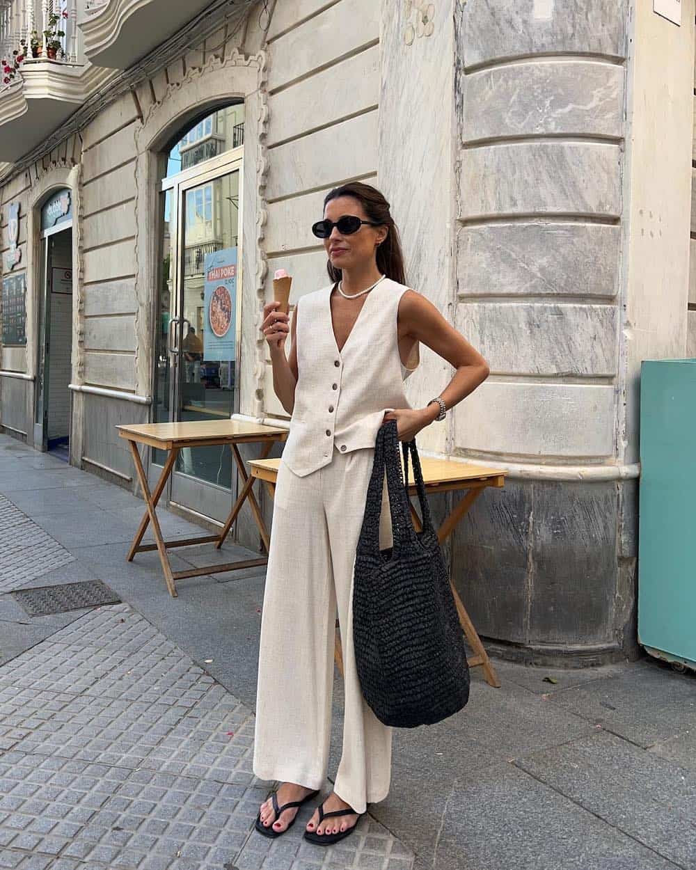 Woman wearing an oatmeal colored linen pant and vest set.