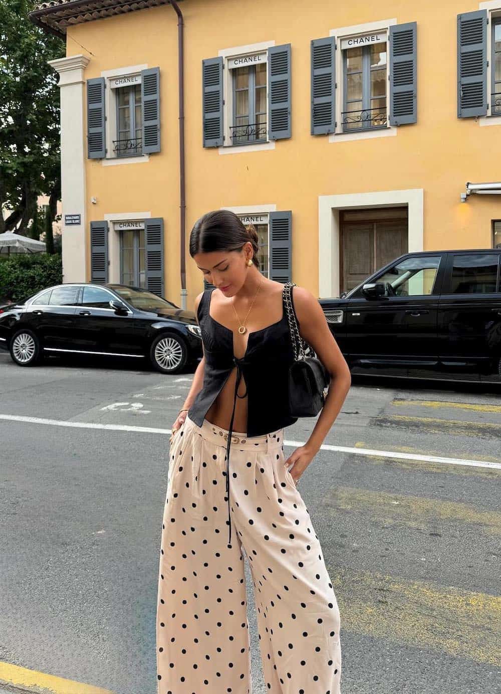a woman wearing wide leg polka dot pants and a tie front black top