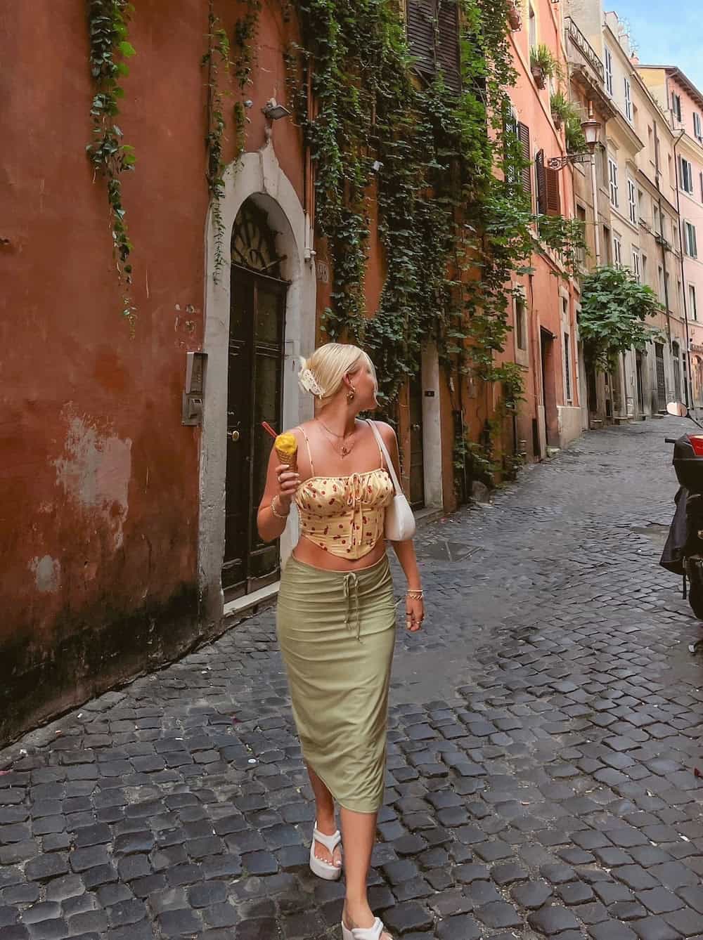 a woman wearing a green midi skirt with a floral tank top and chunky sandals