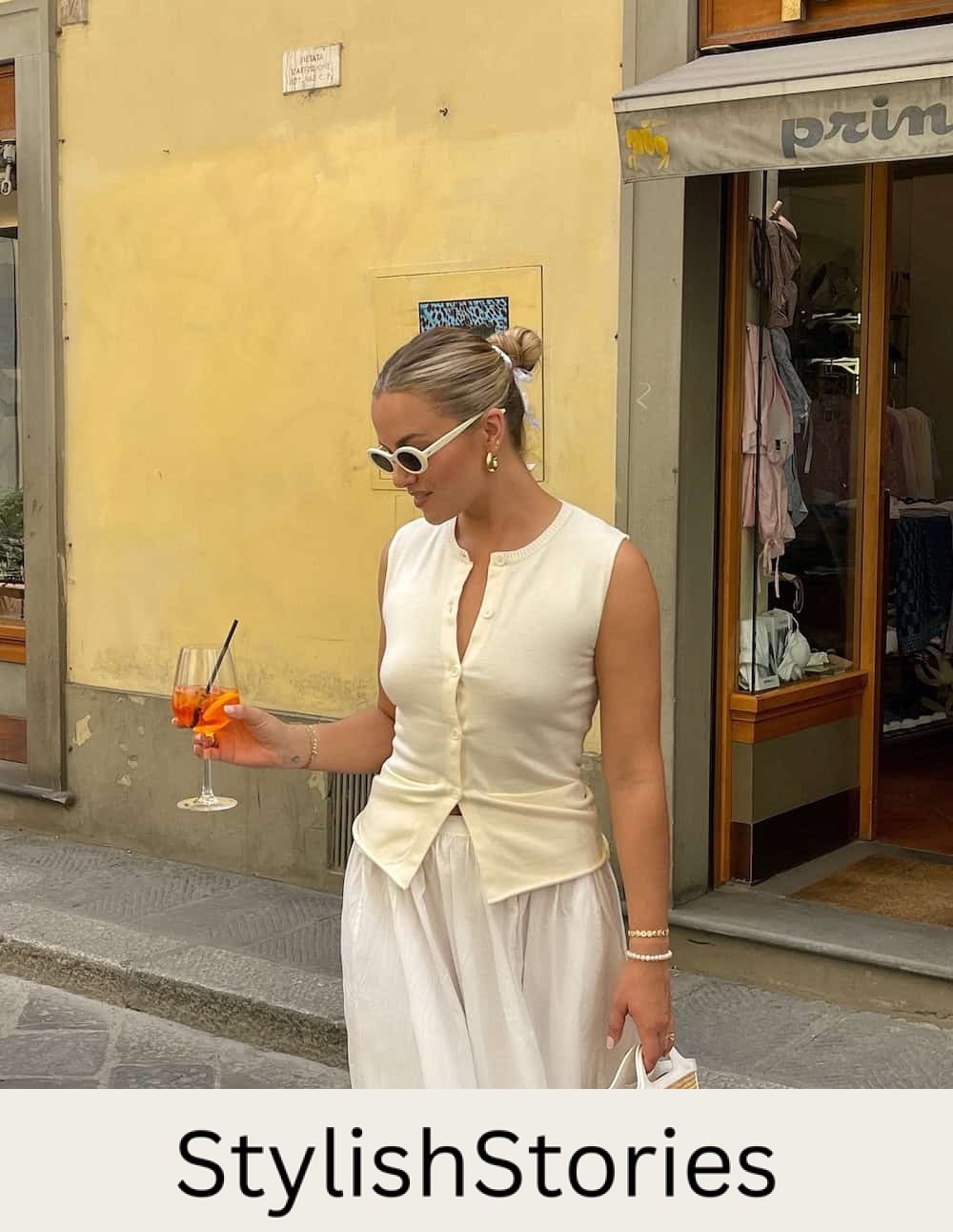 a woman wearing a white flowy linen skirt and a yellow button up sweater vest