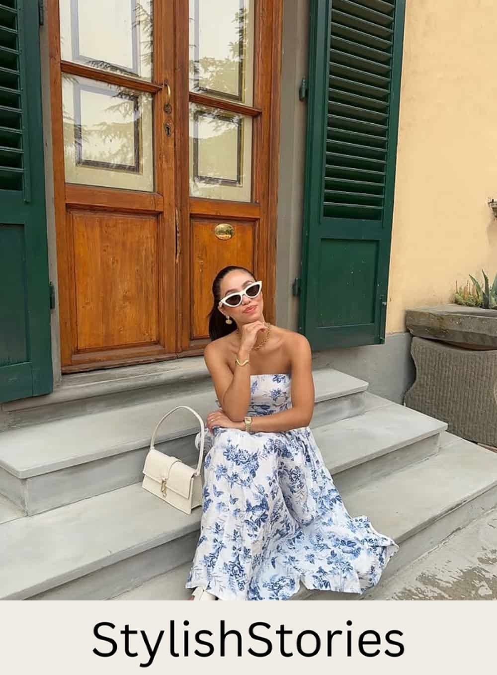 a woman wearing a black and white maxi dress with white sandals and a white shoulder bag