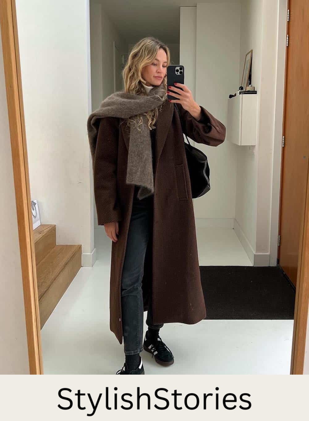 Woman wearing jeans and a long, oversized coat with sneakers.