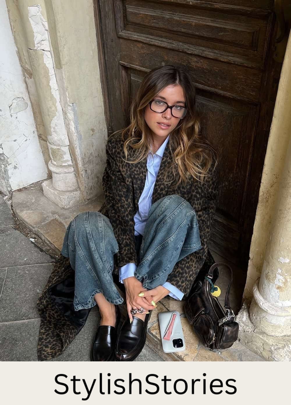 Woman wearing jeans, a button down and a long animal print coat.