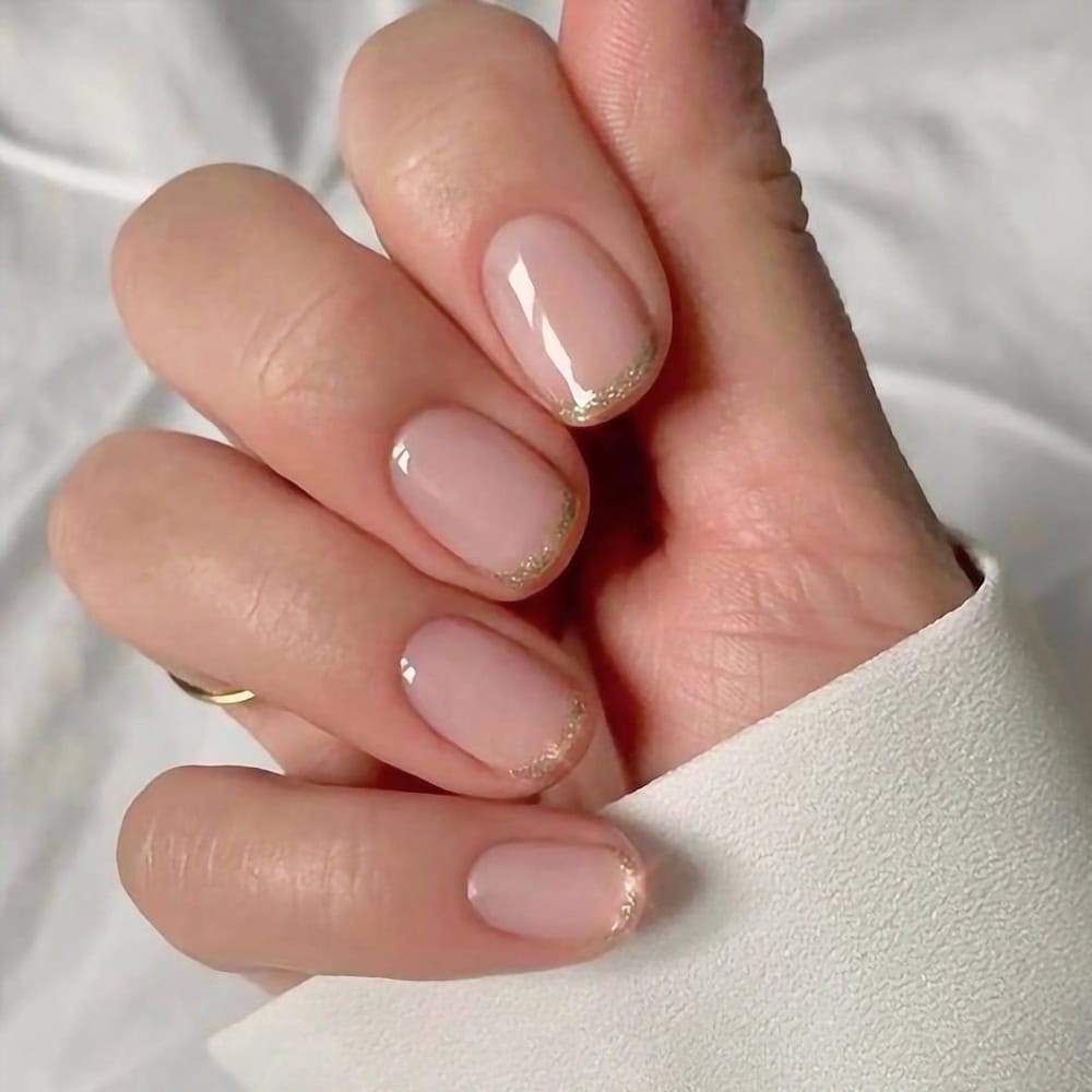 short glossy nude nails with gold glitter tips