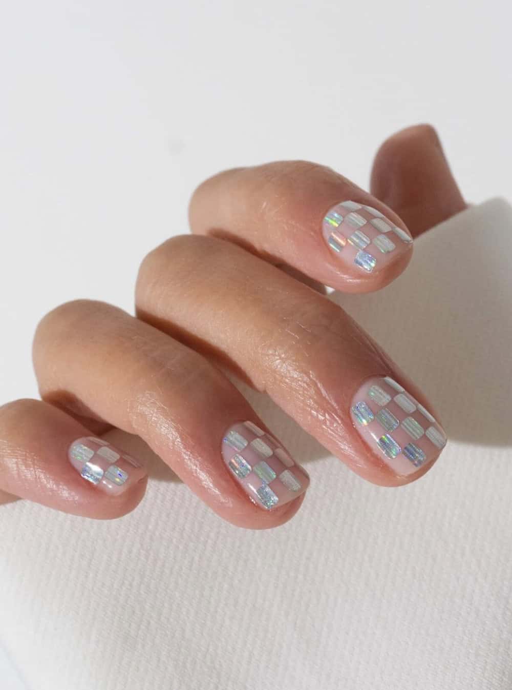 short nails with a nude pink and iridescent checkerboard