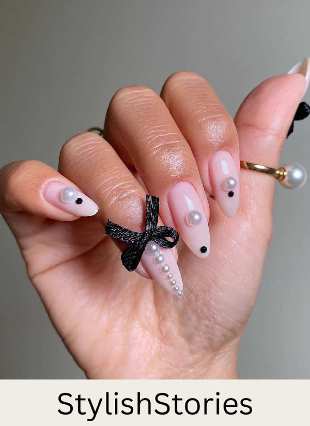long milky white almond nails with black dots and bows and white pearl accents