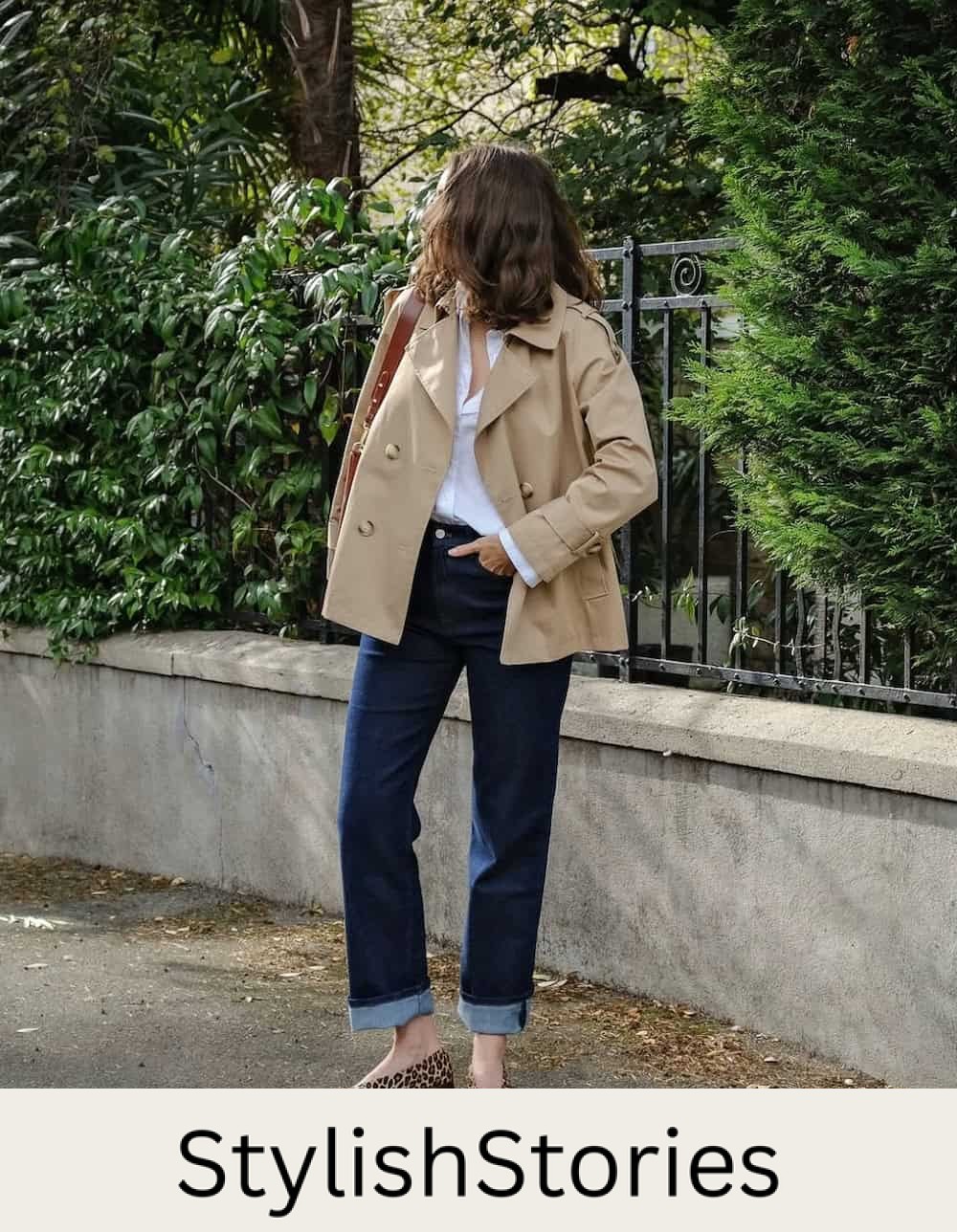 Woman wearing jeans with animal print flats, a white button down and a short trench coat.