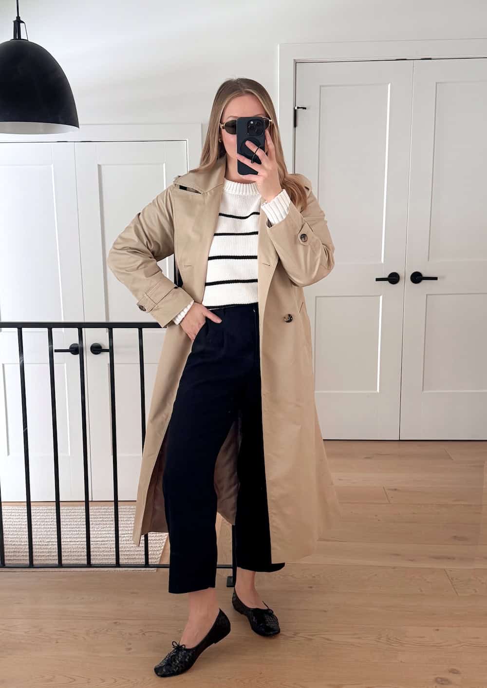 Christal wearing black pants, a white and black sweater and a trench coat.