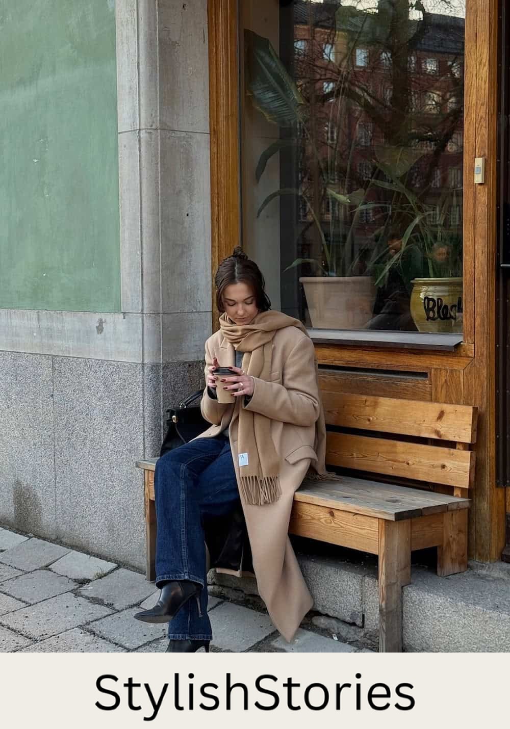 Woman wearing dark jeans with a tan coat and scarf.