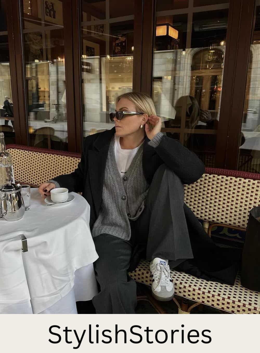 Woman wearing black pants with an oversized sweater over a white tee and sneakers.