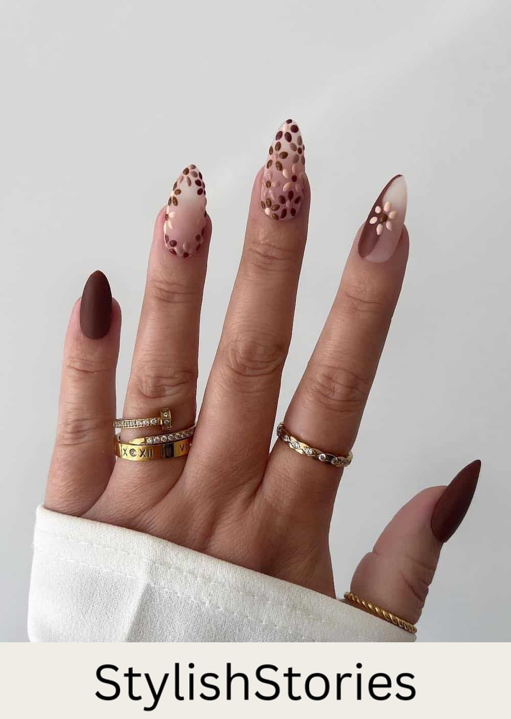 long almond nails featuring floral art, waves, and solid nails with brown and beige polish