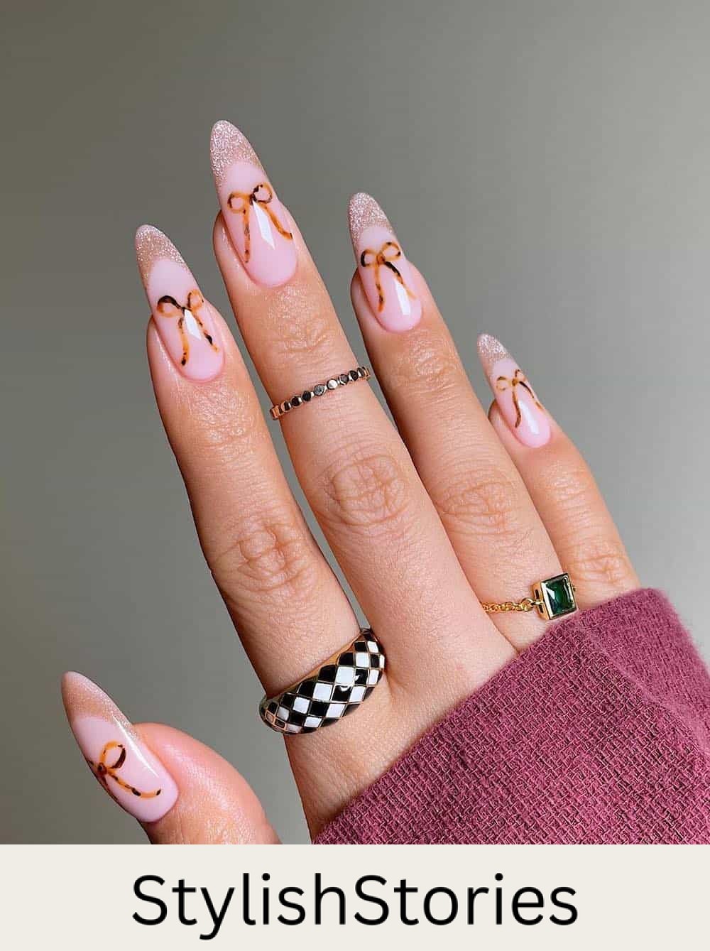 long pink nude almond nails with shimmering tips and brown bows