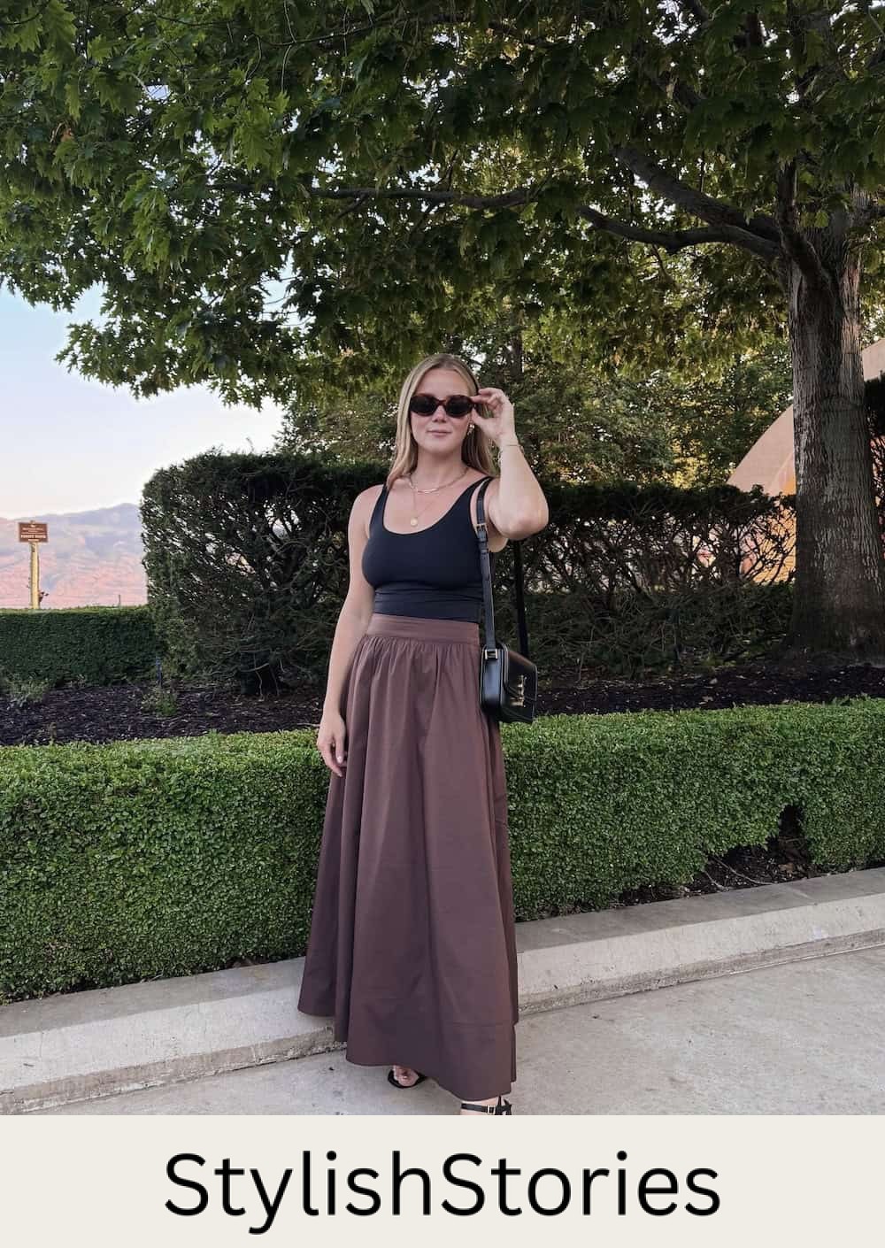 Christal wearing a brown maxi skirt with a black tank top and black heeled sandals.