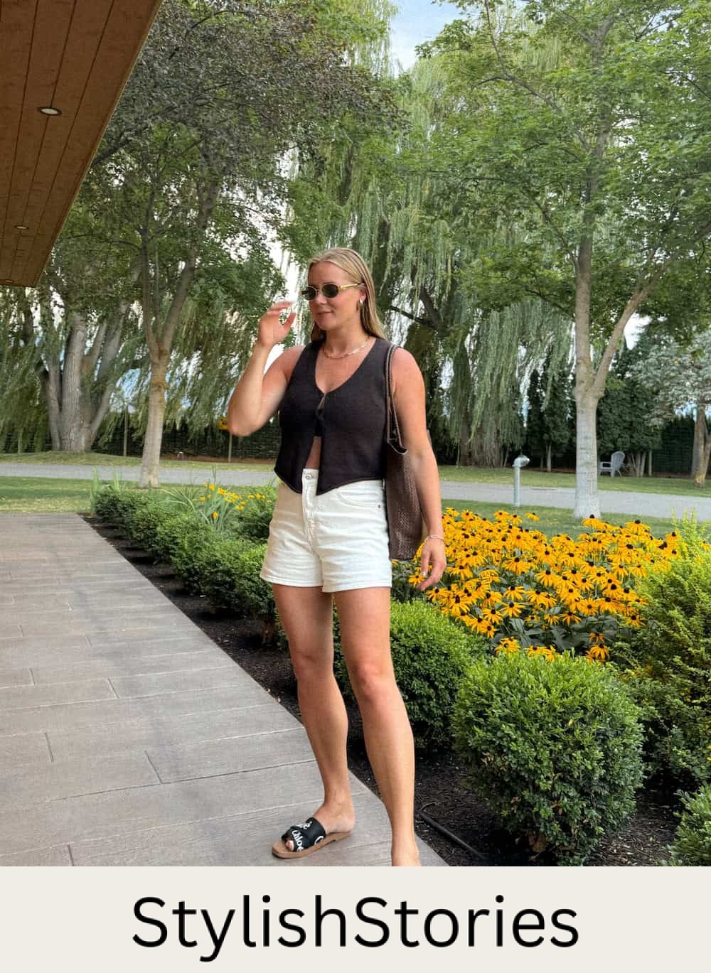 Christal wearing white shorts with a black vest top and black sandals.