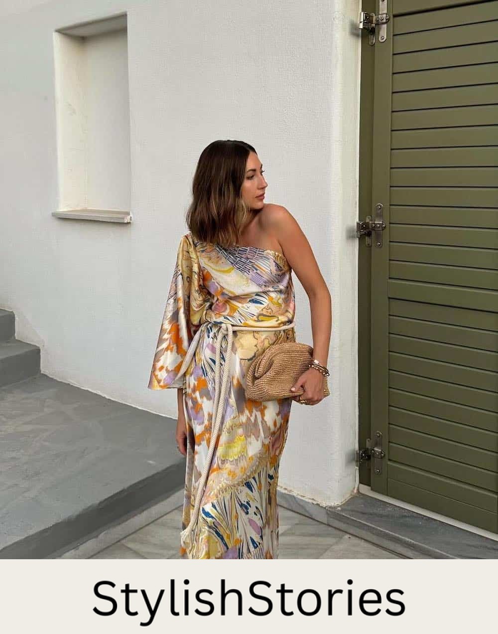 Woman wearing a floral printed multi-color gown with one shoulder detailing.