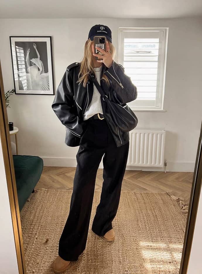 Woman wearing black pants with a grey t shirt and oversized leather jacket.