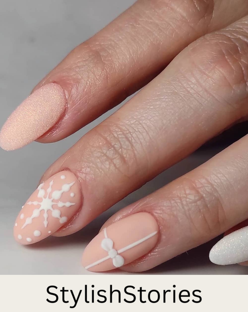 short almond nails with matte beige polish, white snowflakes and christmas present art and glitter accent nails