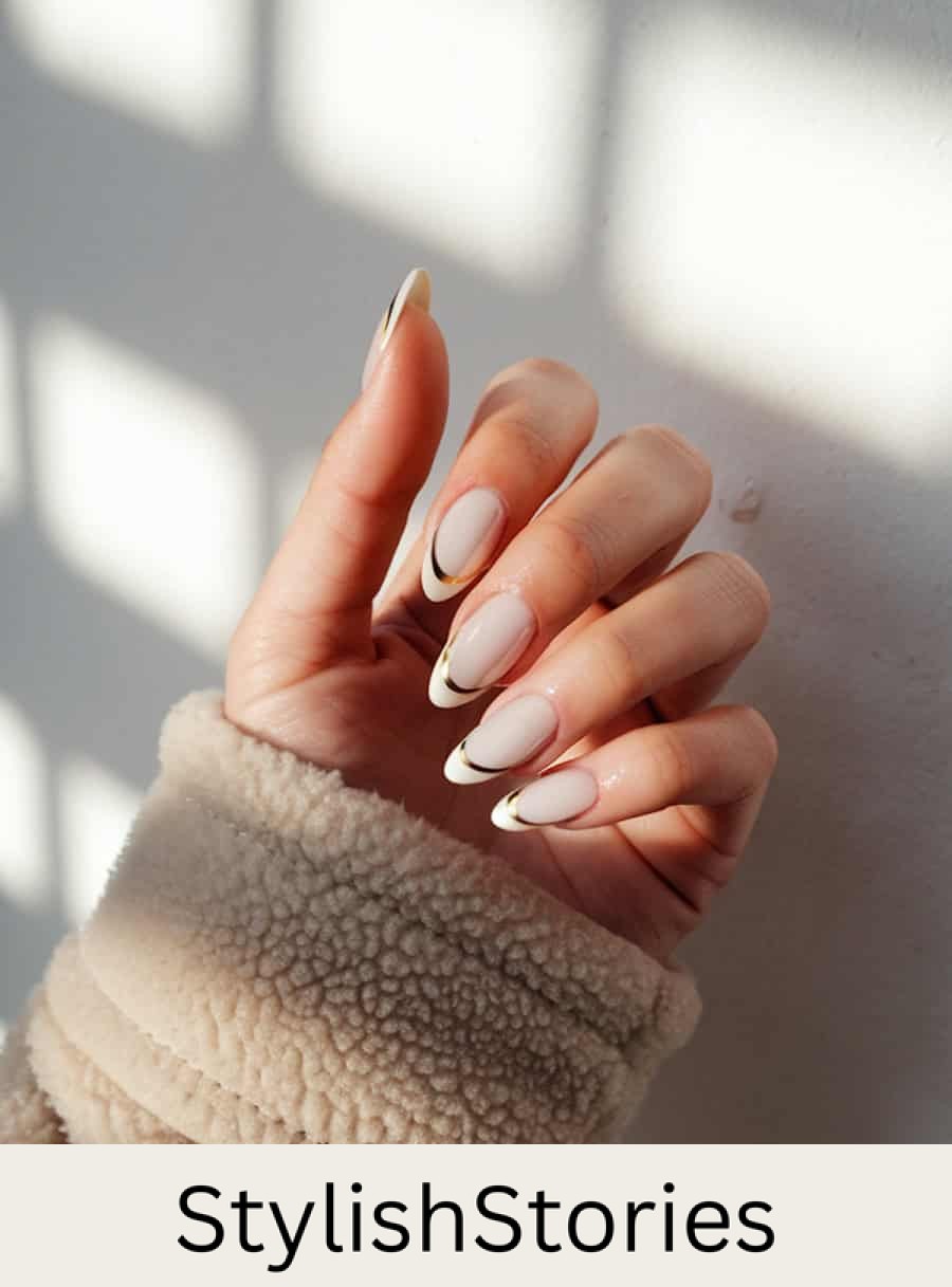 long glossy nude almond nails with white tips and gold bands