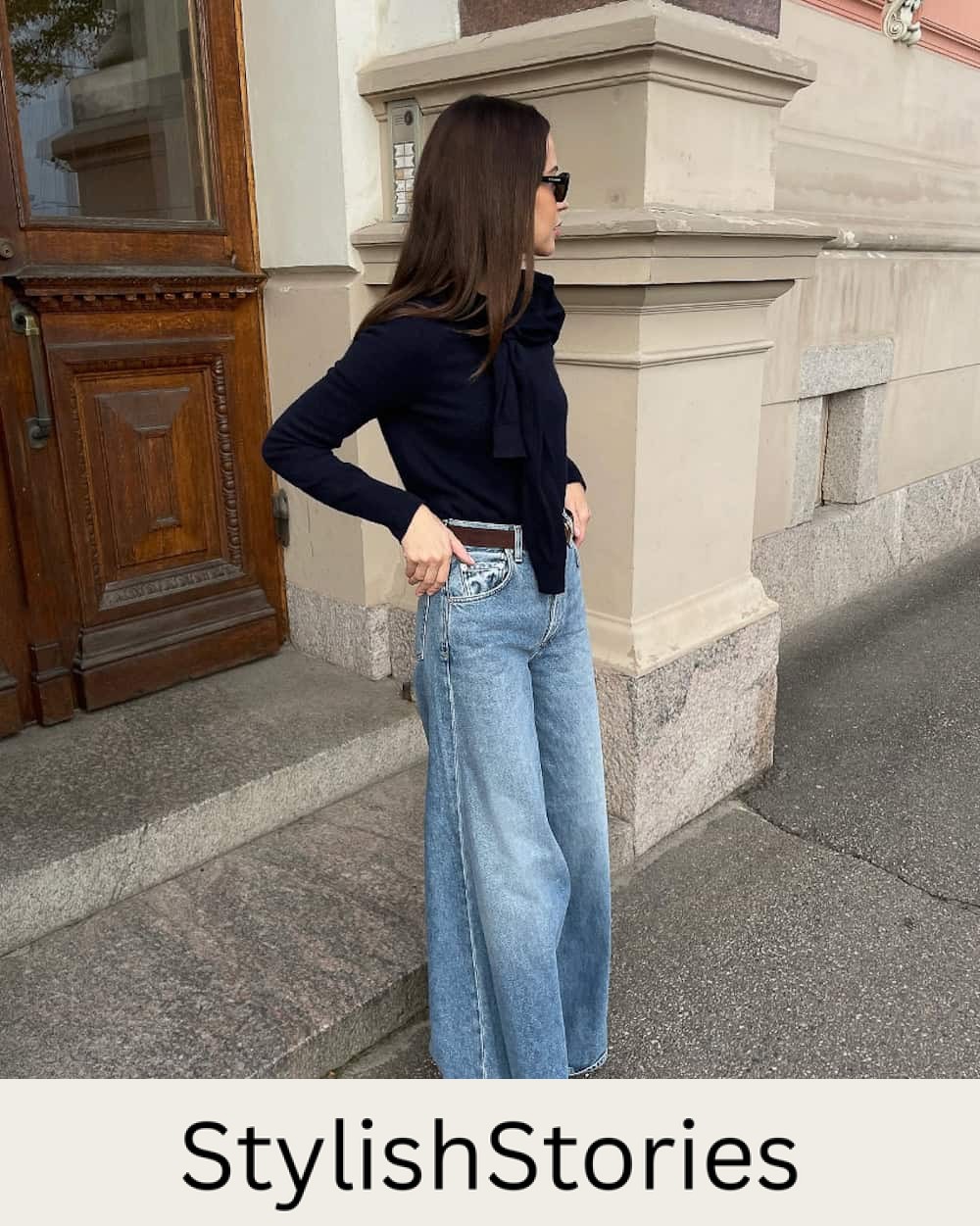 Woman wearing medium wash wide leg jeans and a black sweater.
