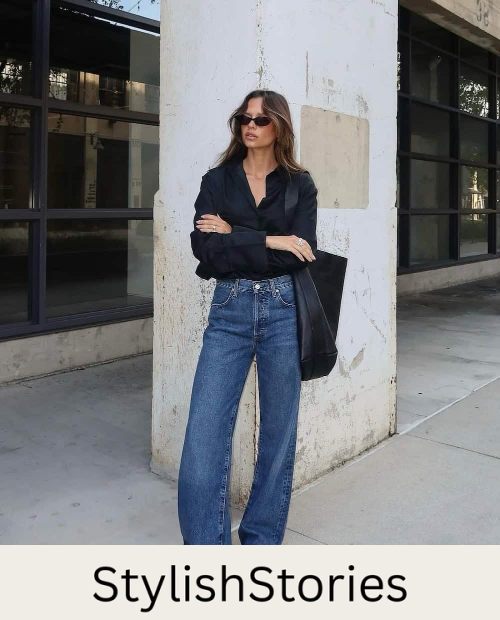 Woman wearing dark wash wide leg jeans and a black button down.