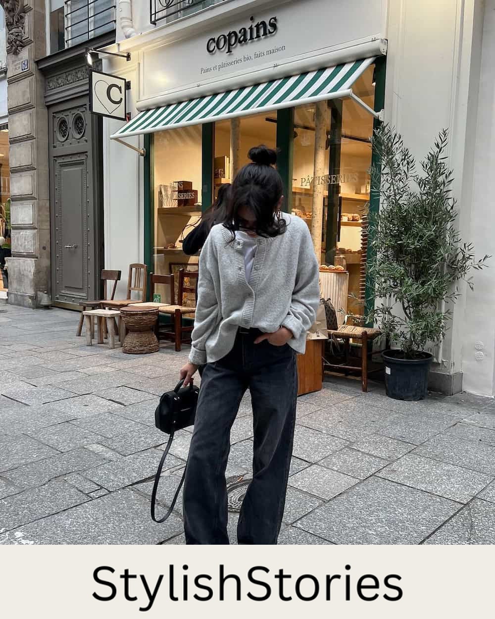 Woman wearing black wide leg jeans and a grey sweater.