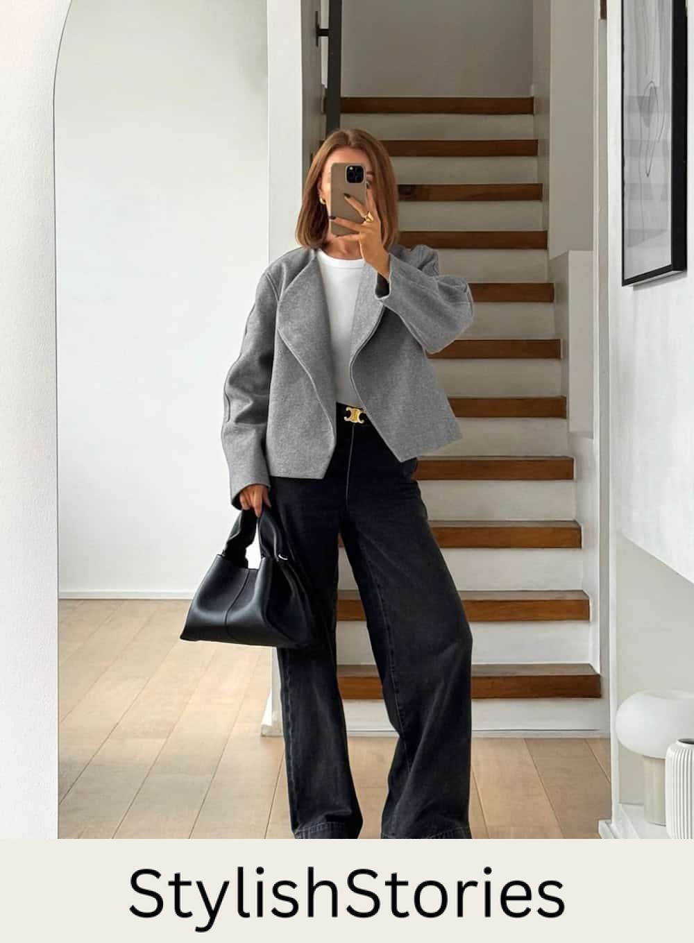 Woman wearing black wide leg jeans with a white sweater and a grey jacket.